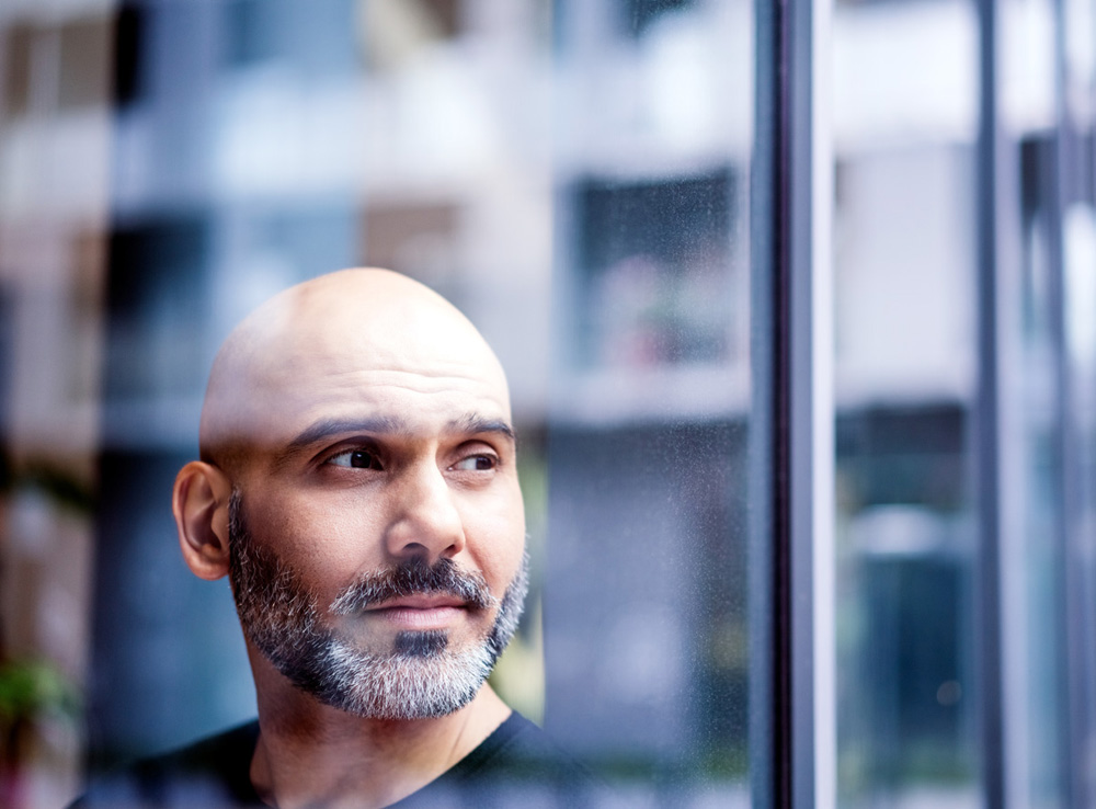 Thoughtful mature businessman looking away in office. Male professional is seen through window. He is at workplace.
