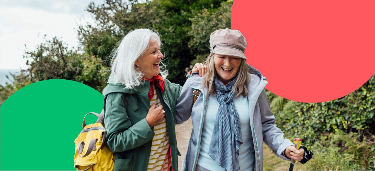 Two elderly women walking through park and laughing