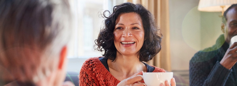 Middle Aged Woman Meeting Friends Around Table In Coffee Shop