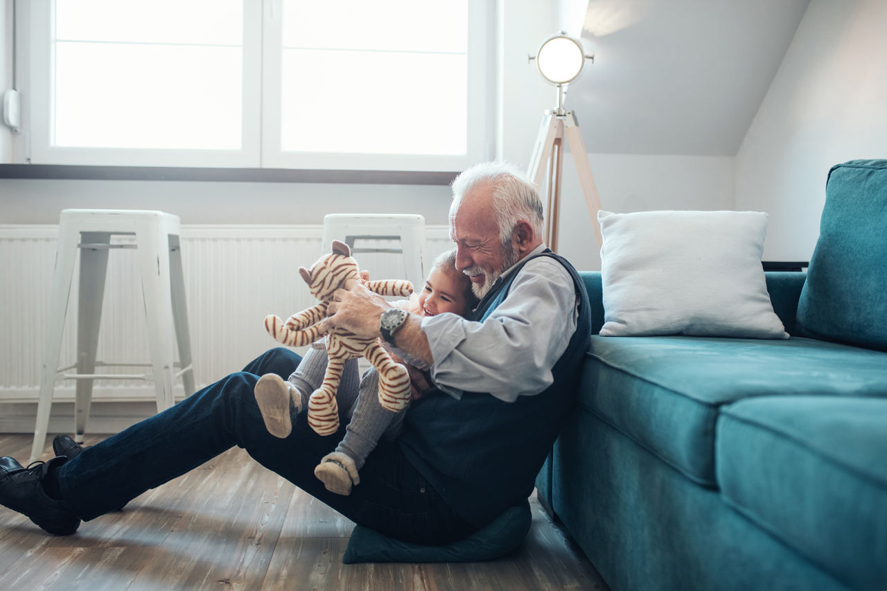Mature man playing with granddaughter at home.